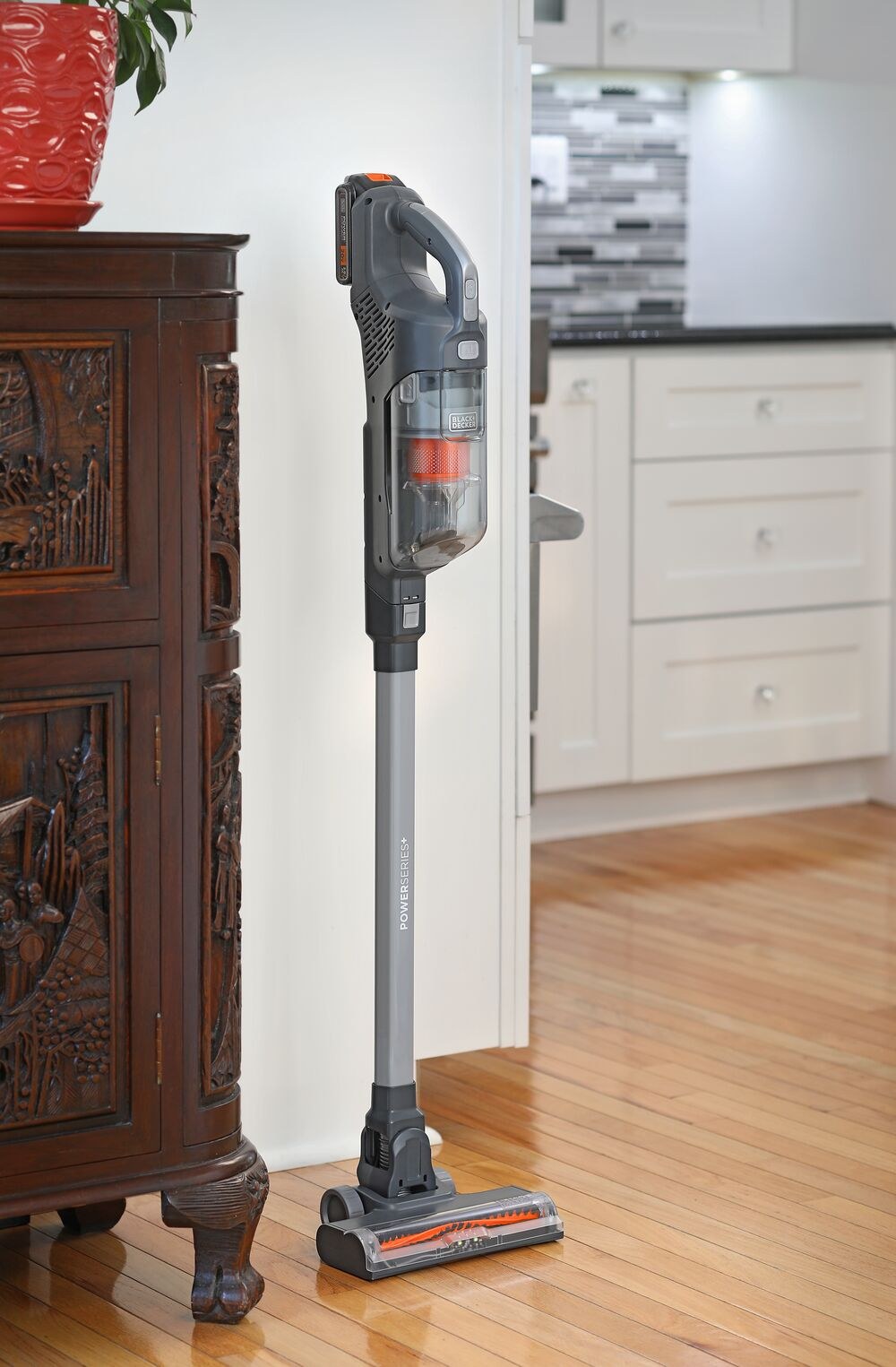 Ασύρματη σκούπα stick BLACK+DECKER BHFEA18D1 POWERSERIES+ σε γκρι και πορτοκαλί, όρθια πάνω σε ξύλινο πάτωμα